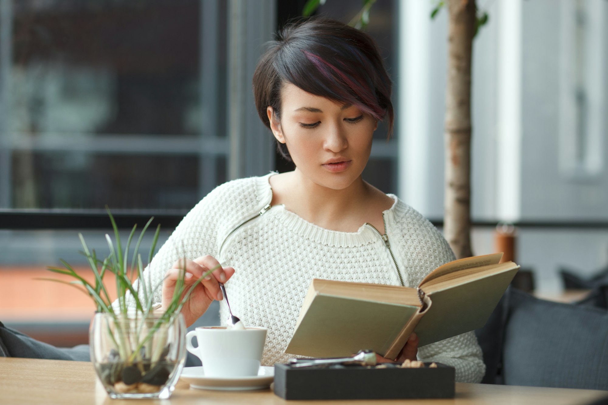 Beautiful woman reading book in cafe